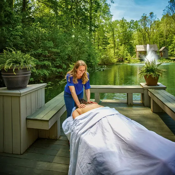 Woman laying on massage table getting a massage outside, with beautiful scenery in the background