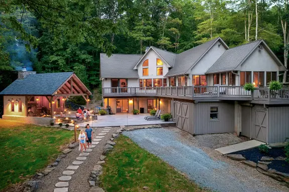 A couple is walking down the stone pathway, stunning cabin and gazebo in the background