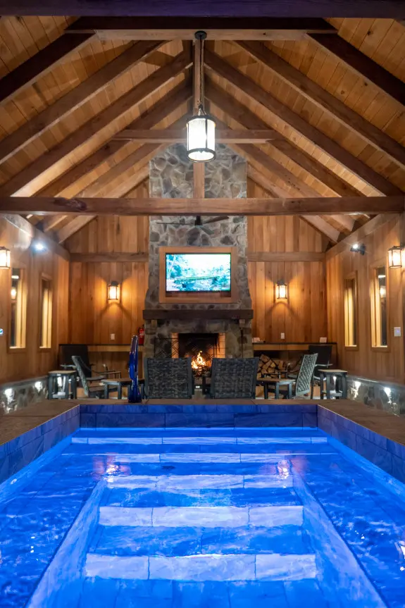 Stone fireplace in background surrounded by seating, with plunge pool in foreground