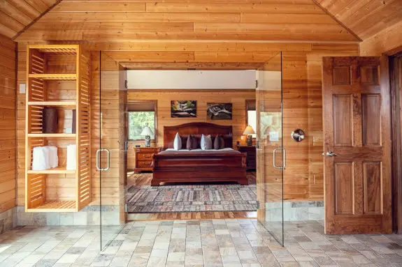 Large wet-room shower, open doors show to king sleigh bed in the bedroom