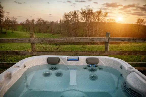 Crystal clear water in the private, secluded hot tub, with rolling hills and fields in the background. 