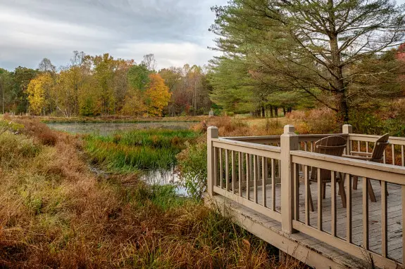 Dock overlooking a pond, with autumn colors on the trees in the background