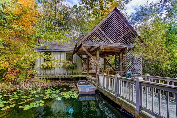 Boat House dock and boat on the lake, with beautiful full trees in the background