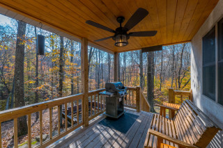 Porch, glider bench and gas grill, with forest surrounding
