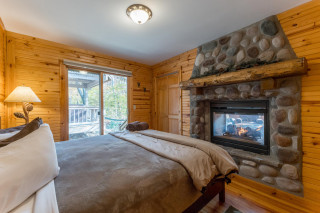 King bed with stone fireplace, sliding glass door leading out to hot tub gazebo
