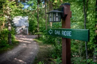 Sign with light overhead, Oak Ridge and an arrow on the sign, cabin in the background