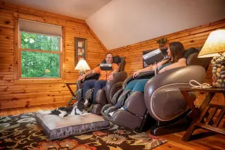 Man and woman in massage chairs, dog on a dog bed laying in front of them