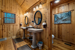Photo of a wood paneled bathroom with a pair of pedestal sinks