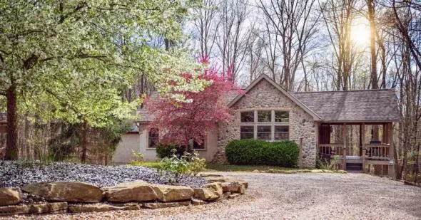 Cabin with stone exterior, spring flowers blooming in front of the cabin