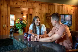 A woman and man sit at a counter, with coffee mugs