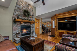 Living room with stone fireplace, flat screen TV, coffee table
