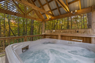 Bubbling clean hot tub under a gazebo, forest views surrounding