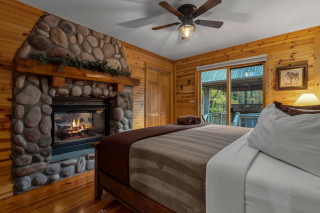 Bedroom with king bed, stone fireplace, and sliding glass doors leading out to hot tub. 