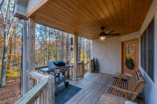 Porch with gliding bench, gas grill, and beautiful forest surrounding. 