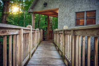 A ramp leads to the cabin porch. Forest in background. 