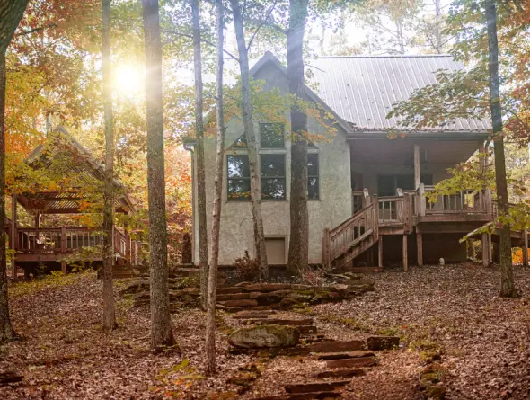 Cabin surrounded by fall leaves, stone path in foreground