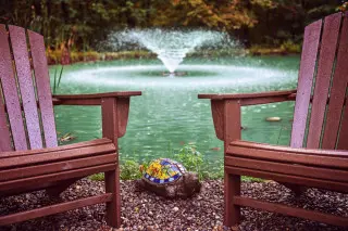 Pond with a fountain, Adirondack chairs 