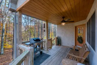 Porch with gliding bench, gas grill, and beautiful forest surrounding. 